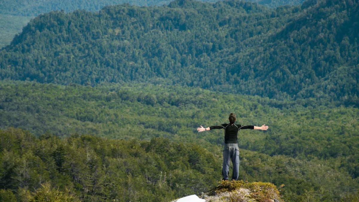 A man with outstretched arms taking in the scenic mountain landscape.